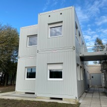 Modulair containergebouw in lichtgrijs.